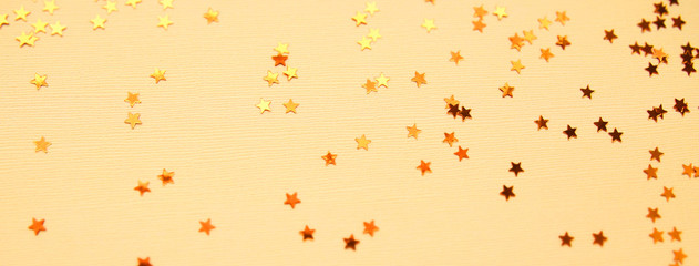 Golden stars glitter on yellow paper background