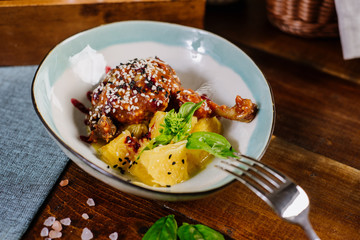 Baked chicken leg with sauce and fruits on the wooden background