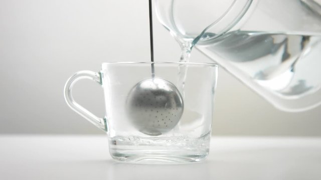 transparent cup with a tea infuser spoon. Brewing tea minimalist footage
