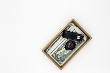 Car key and banknotes in a small gift cardboard box on white bac