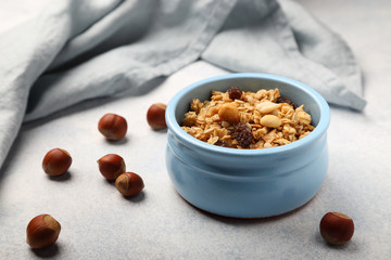 Baked granola, with hazelnuts, raisins and peanuts, in a blue plate, on a gray-blue background.