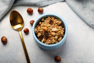 Baked muesli, with hazelnuts, raisins and peanuts, in a blue plate, on a gray-blue background.