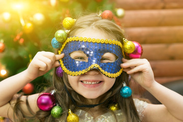 The joy of the girl from the New Year holiday. Girl with balls her hair with a carnival mask celebrates Christmas