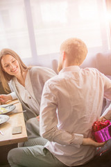 a guy gives a girl a gift on a date in a cafe