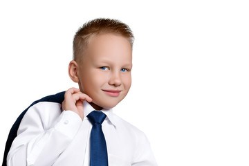 Cute European boy with smile in a white shirt with a blue tie and a jacket on his shoulder looking at the camera isolated on a white background. Concept of a successful businessman, leadership.