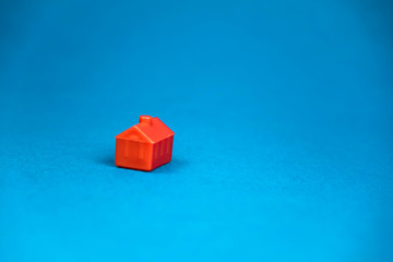 red miniature lonely house standing on a blue background
