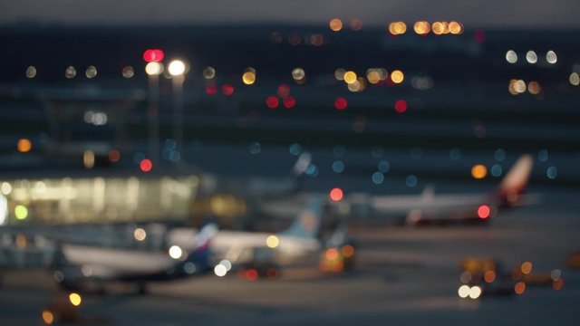 A blurred night airport area with a multitude of light spots - car lights, plane lights, building lights