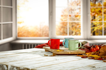 Autumn desk with mug and blurred fall window space 