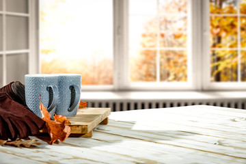 Autumn desk with mug and blurred fall window space 