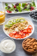 Healthy breakfast served with plate of yogurt muesli kiwi strawberries and banana