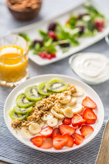 Healthy breakfast served with plate of yogurt muesli kiwi strawberries and banana