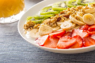 Healthy breakfast served with plate of yogurt muesli kiwi strawberries and banana