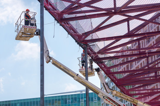 Professional installation work on a construction building site. Assemblers perform high-altitude installation works on the telescopic  boom lifts platforms. Installation of steel beams and safety nets