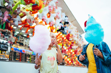Boy and girl eating sweet cotton at the amusement park
