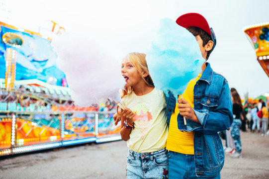 Boy and girl eating sweet cotton at the amusement park