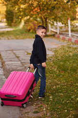 A boy with a suitcase is on the road on a journey, preparing for the trip