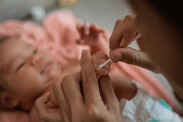 young mother cleaning between finger folds of little girl using cotton bud after take a bath