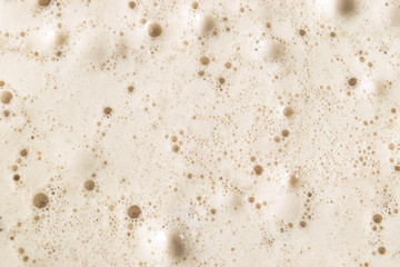 Macro shot Beer foam bubbles  texture background. Craft beer flowing foam with sparkling bubbles. Beer foam texture close up.