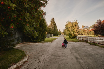 A boy with a suitcase is on the road on a journey, preparing for the trip