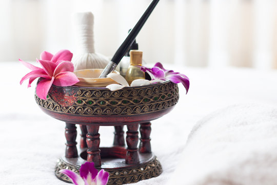 Spa Thai massage accessories in luxury salon on white towel in vase. Oil and beauty care equipment for relaxation and treatment indoors.