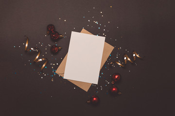 Holiday and invitation mockup. Empty card in kraft envelope on dark background decorated with...