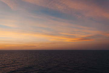 Horizon of the sea and orange-colored clouds after sunset