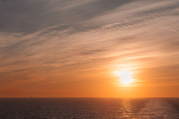 Naklejka na ściany i meble Sunset and colorful sky on the sea with a wake left by a cruise ship