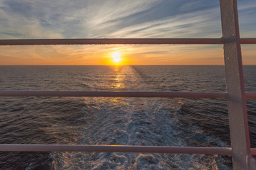 Sunset and wake left on the sea by a cruise ship