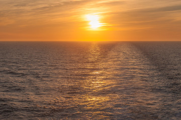 Sunset on the sea where you can see the wake left by a cruise ship