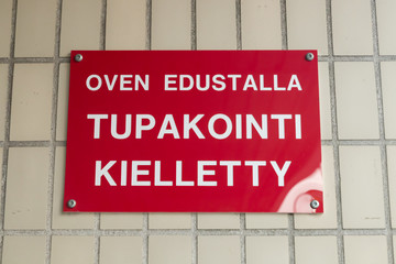 No smoking sign on the wall in Finnish language - No smoking in front of the door.