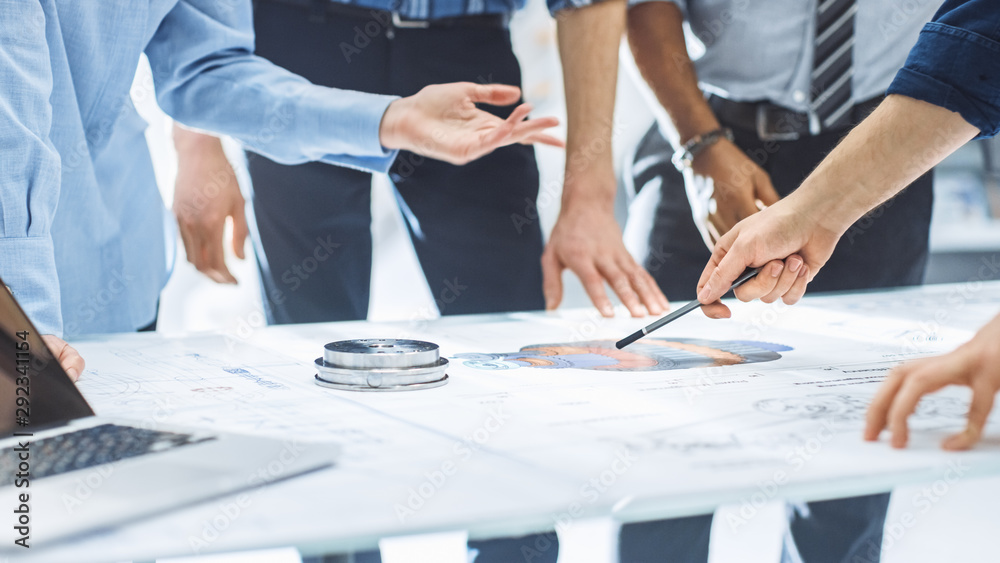 Poster Industrial Engineering Facility: Close-up on Hands of Group of Engineers, Technicians and Specialists on a Meeting, Tracing Lines and Analysing Engine Design Technical Drafts Laying on the Table