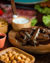 Black bread strips with garlic, oil and cheese grates on top and yogurt