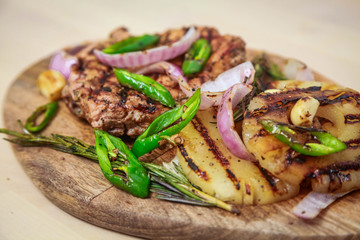 Grilled pork with pineapple, red onion and hot green pepper. Serve on a wooden board.