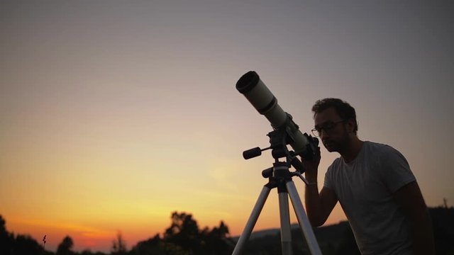 Astronomer with a telescope watching at the sky.