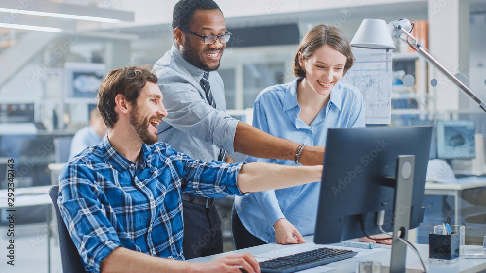 Poster In the Industrial Engineering Facility: Male Engineer Working on Desktop Computer, Female Chief Engineer and Project Manager Discuss and Explain to Him Project Details. They Smile, Joke and Cheer