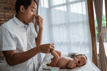 portrait of asian father change baby diapers at home