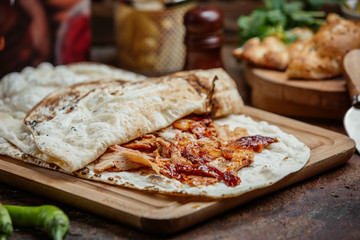 Chicken kebab doner with ketchup inside of flatbread on wooden board