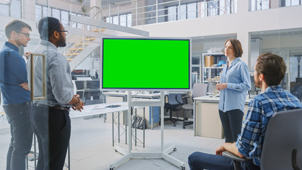 In the In Industrial Design Facility Team of Engineers and Technicians have a Meeting, Female Specialist Leads Briefing, Talks and Use Digital Interactive Whiteboard with Green Mock-up Screen  - obrazy, fototapety, plakaty