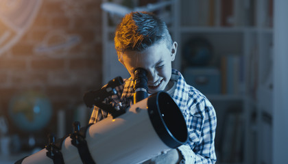 Cute boy watching stars through a telescope