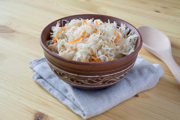 Sour cabbage fermented sauerkraut with carrot in a bowl. Marinated cabbage on wooden background