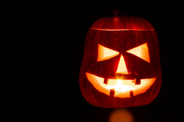 Halloween pumpkin with a scary face on a black background. Jack o lantern. Autumn holiday.