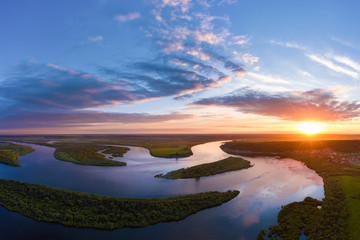 Fototapeta na wymiar Aerial panoramic landscape with sunset over the river with islands and beautiful clouds on the sky.