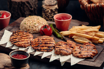 Grilled chicken patties with pilaff, french fries and ketchup