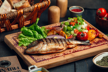 Grilled fish with fresh vegetable salad, lettuce and sumac sprinkles
