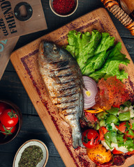 Grilled fish with vegetable salad, onion and sumac sprinkles