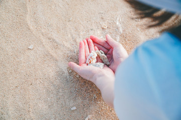 サラサラの砂浜に手と貝殻（東洋一美しい与那覇前浜ビーチ）