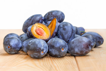 Many plums on wooden table with white background.