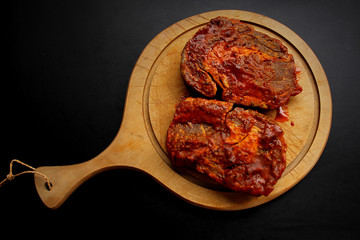 raw meat, beef steaks marinated in red marinade, lie on a wooden round board, cooking concept, horizontal, close-up