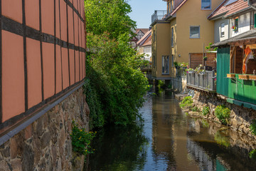 Fototapeta na wymiar A small river with a green shore through a small town