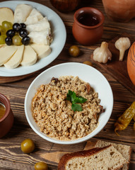 A bowl of minced meat mix with crushed walnut served with cheese plate and bread
